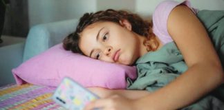 A young woman with a glum expression scrolls on her smartphone. GETTY IMAGES