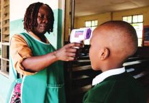 A woman uses a thermometer gun to check the temperature of a school pupil. Uganda introduced tightened screening and other protocols as soon as the Ebola outbreak was declared in May. GETTY IMAGES