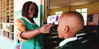 A woman uses a thermometer gun to check the temperature of a school pupil. Uganda introduced tightened screening and other protocols as soon as the Ebola outbreak was declared in May. GETTY IMAGES