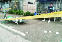 A police officer stands guard at the crime scene in Barangay Dangula-an, Anilao, Iloilo, where a 60-year-old man was gunned down by riding-in-tandem suspects on July 28, 2026. PHOTO COURTESY OF XFM RADYO PATROL ILOILO