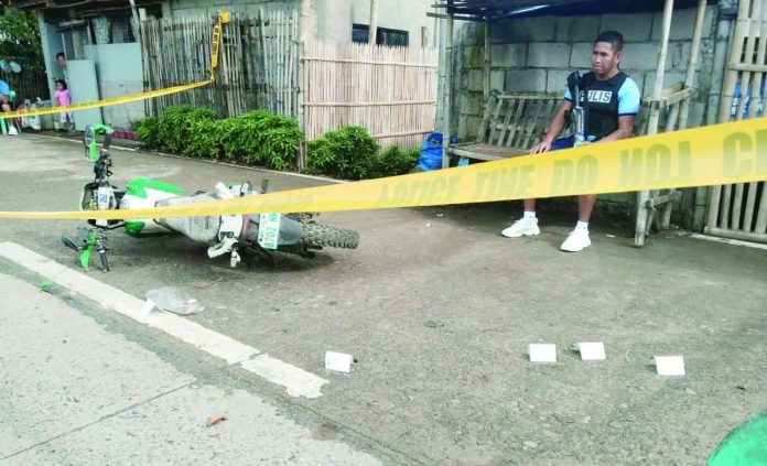 A police officer stands guard at the crime scene in Barangay Dangula-an, Anilao, Iloilo, where a 60-year-old man was gunned down by riding-in-tandem suspects on July 28, 2026. PHOTO COURTESY OF XFM RADYO PATROL ILOILO