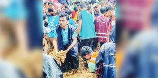 A large group of volunteers and aid workers stand in deep mud during heavy rain, working together at the site of a landslide by a school at a refugee camp in Cox’s Bazar, Bangladesh. AFP VIA GETTY IMAGES