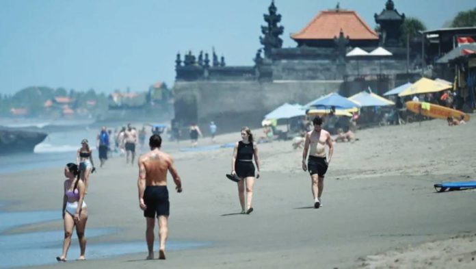Tourists walk on a beach in Bali, where its usually bustling beaches turn empty during Nyepi, an annual Hindu holiday. AFP VIA GETTY IMAGES