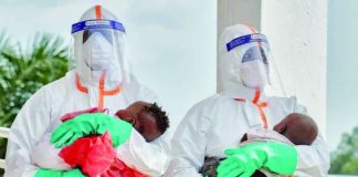 Two health workers in hazard suits each hold a young baby in the Democratic Republic of Congo. Ebola, which spreads through contact with bodily fluids, has killed 15,000 people across Africa over the last 50 years. REUTERS