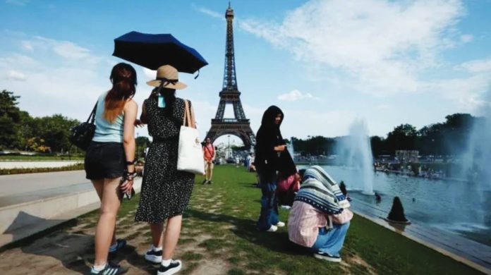 France Women shelter from the heat under a black umbrella at the Trocadero Fountain by the Eiffel Tower, in Paris, France. Other people are seated next to the river. EPA