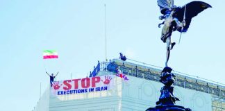 Protesters hold a banner saying “stop executions in Iran” and wave an Iranian flag during a demonstration on the roof of the Trocadero, overlooking Piccadilly Circus, central London. LIGHTROCKET VIA GETTY IMAGES