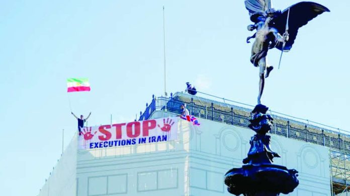 Protesters hold a banner saying “stop executions in Iran” and wave an Iranian flag during a demonstration on the roof of the Trocadero, overlooking Piccadilly Circus, central London. LIGHTROCKET VIA GETTY IMAGES