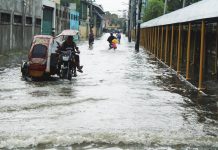 Residents navigate a flooded street near La Paz National High School in Barangay San Roque, La Paz, Iloilo City on Tuesday morning, August 18, 2026. Intense rainfall submerged 65 barangays across the city, exposing severe limitations in the city's existing drainage system. ALLEN ANIMAS/PN