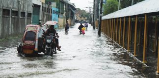 Residents navigate a flooded street near La Paz National High School in Barangay San Roque, La Paz, Iloilo City on Tuesday morning, August 18, 2026. Intense rainfall submerged 65 barangays across the city, exposing severe limitations in the city's existing drainage system. ALLEN ANIMAS/PN
