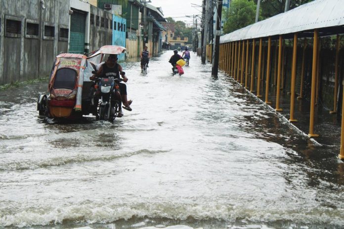 drainage Residents navigate a flooded street near La Paz National High School in Barangay San Roque, La Paz, Iloilo City on Tuesday morning, August 18, 2026. Intense rainfall submerged 65 barangays across the city, exposing severe limitations in the city's existing drainage system. ALLEN ANIMAS/PN
