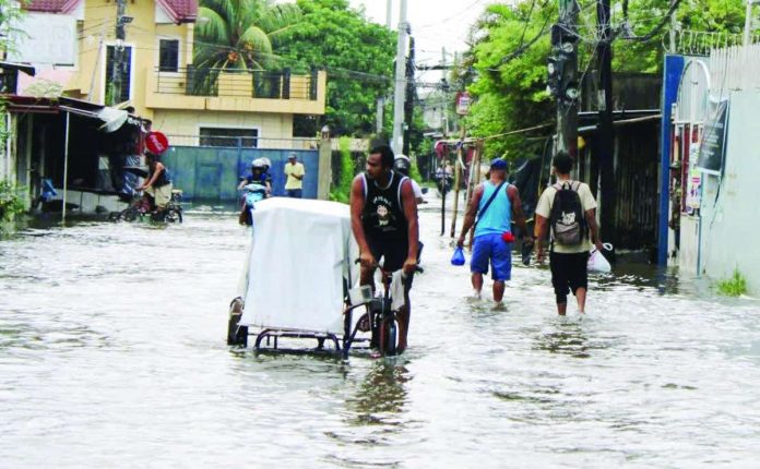 WADING THROUGH ‘HABAGAT.’ Residents navigate a flooded street in La Paz, Iloilo City as persistent rains brought by the southwest monsoon, or habagat, continue to affect Western Visayas. The state weather bureau warned that days of rainfall have saturated the ground and waterways, increasing the risk of flooding and rain-induced landslides, particularly in low-lying and vulnerable communities. ALLEN ANIMAS/PN
