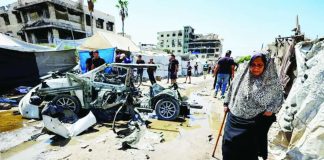 An elderly woman walks past a destroyed vehicle following an Israeli strike in the Rimal neighborhood of Gaza City on September 1, 2026. AFP VIA GETTY IMAGES