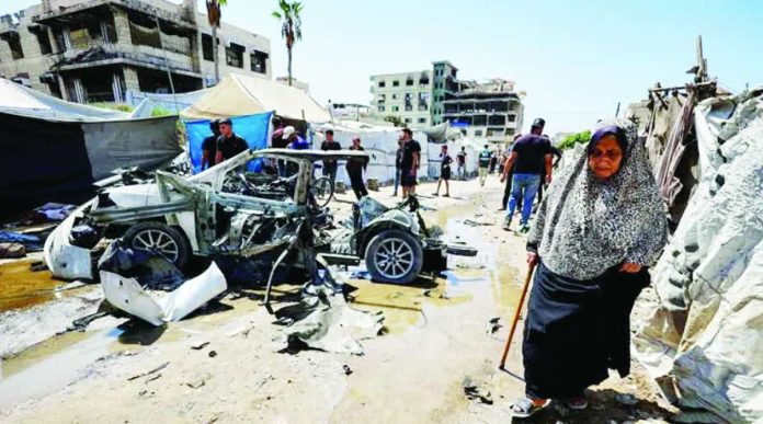 An elderly woman walks past a destroyed vehicle following an Israeli strike in the Rimal neighborhood of Gaza City on September 1, 2026. AFP VIA GETTY IMAGES