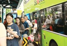 A small crowd of people alight from a green double-decker bus in Singapore. GETTY IMAGES