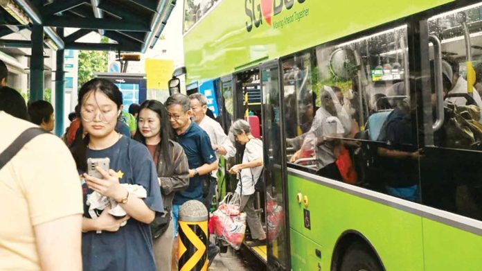 A small crowd of people alight from a green double-decker bus in Singapore. GETTY IMAGES