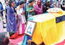 Family members and mourners attend a ceremony to receive the coffin with the body of King Oyo Nyimba Kabamba Iguru Rukidi IV at Entebbe airport in Uganda. The casket is draped in the Tooro kingdom flag and the Ugandan flag. A portrait of the monarch has been placed at the front of the coffin. REUTERS