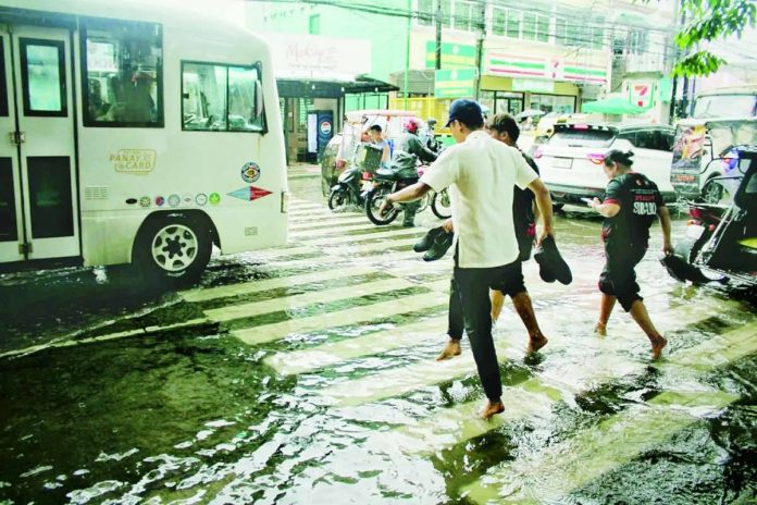 WADING THROUGH MONDAY. Several students take off their shoes and socks and roll up their pants to cross a flooded pedestrian lane along Burgos Street in front of Iloilo Science and Technology University (ISAT-U) in La Paz, Iloilo City on Monday morning, September 7, 2026. Sudden heavy rains on Monday morning caused localized flooding, slowing down traffic and impacting pedestrians and commuters across the city. ALLEN ANIMAS/PN