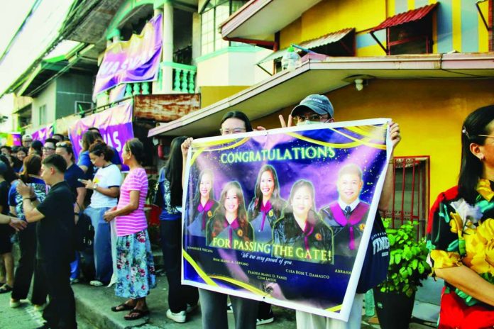 neljoy_bar1_copy_compressed_resized Law students and supporters gather outside Central Philippine University in Jaro, Iloilo City, displaying banners and cheering on aspiring lawyers taking the 2026 Bar Examinations. CPU is the lone Bar testing center for Western Visayas and the Negros Island Region, drawing examinees from law schools across the two regions. ALLEN ANIMAS/PN