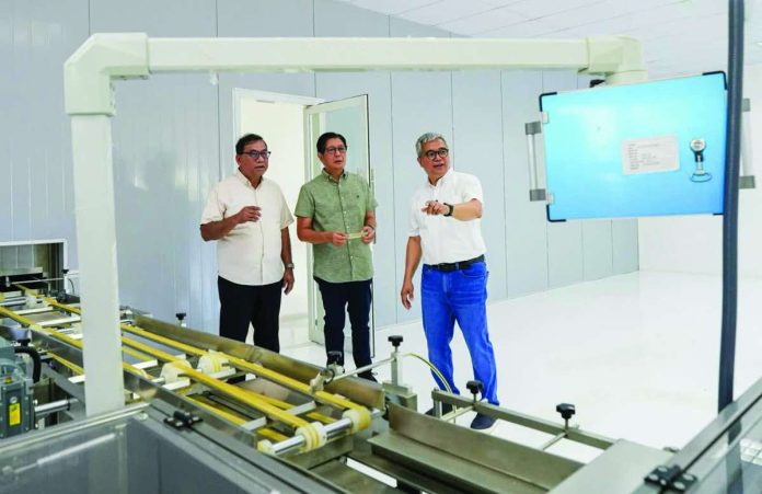 snack_plant_copy_compressed_resized President Ferdinand R. Marcos Jr. (center), accompanied by Department of Science and Technology Secretary Renato U. Solidum Jr., inspects the facilities of Nutridense Food Manufacturing Corporation, a government-assisted private company that grew from a micro, small, and medium enterprise into a model of technology-driven food manufacturing in Pangasinan, on Sept. 17, 2026. PRESIDENTIAL COMMUNICATIONS OFFICE PHOTO