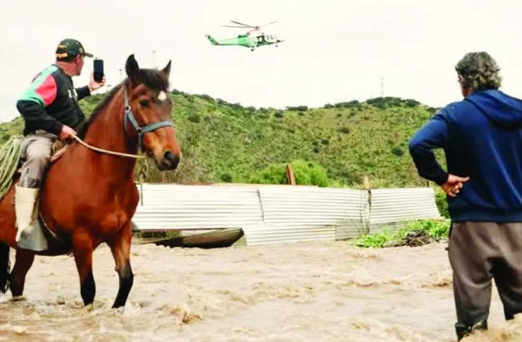 Residents airlifted to safety after flooding in central Chile A man on a horse takes a video of a helicopter hovering overhead. Another man stands nearby, with the water reaches his knees. The Mapocho river in central Chile burst its banks after heavy rains. JAVIER TORRES/EPA/SHUTTERSTOCK