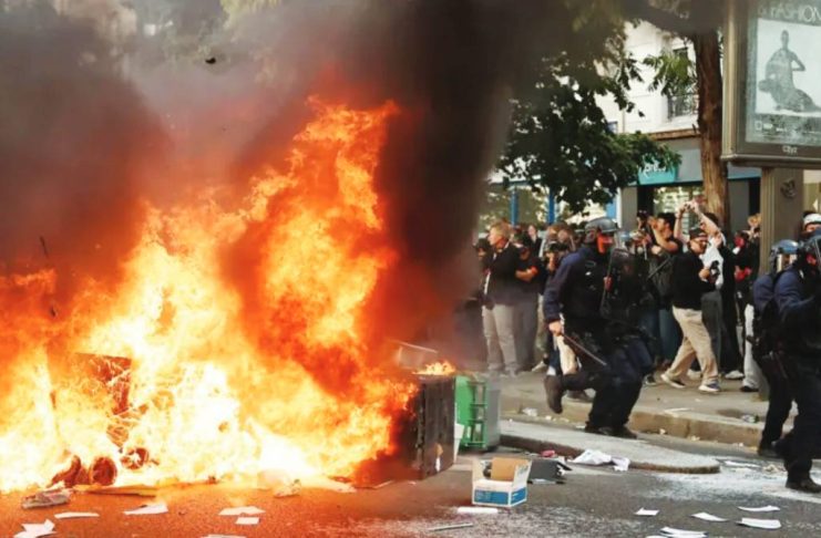 France halts use of stun grenades after boy’s hand blown off in protests A large fire burns on a road in Paris beside which five officers in riot gear walk past a crowd observing the flames. Hundreds of thousands of protesters take to the streets across France. REUTERS