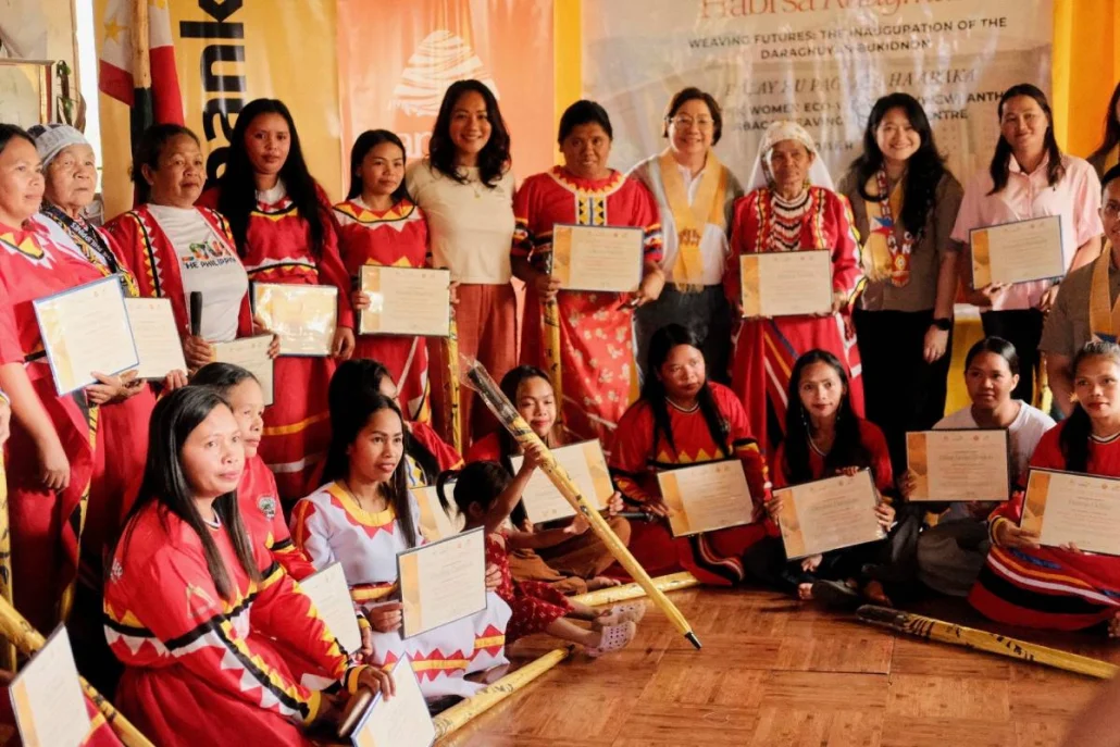 Weaving heritage, building futures. The launch of the MWEW ANTHILL Abaca Weaving Training Centre in Bukidnon celebrated 20 Daraghuyan women weavers who completed their weaving training, recognising their commitment to carrying forward the community’s traditional Pinangabol weaving. Through the Maybank Women Eco-Weavers (MWEW) Programme, Maybank Foundation and ANTHILL Fabric Gallery are supporting these women to strengthen their skills, sustain their cultural heritage and build new livelihood opportunities through their craft. Featuring the women weavers who have completed their training, together with Anya Joy Lim, Princess Ant/Co-Founder of ANTHILL Fabrics Gallery (sixth from the left in beige T-shirt); Salome Tarino, Community Manager of Daraghuyan Bukidnon Balay Hu Paglala Ha Abaca (seventh from left in red tribal dress); Annie Lim, Queen Ant/Co-Founder, ANTHILL Fabric Gallery (fourth from right in white shirt), Bae Inatlawan Adelina Tarino, Tribal Leader, Daraghuyan Bukidnon Tribe (third from right in red tribal dress and white headscarf); Noor Fadzlin Ariffin, Head, Community Empowerment, Maybank Foundation (second from right in green army shirt); Jonnalyn Mangga, Trainer/Weaver, Daraghuyan Bukidnon Tribe (first from right in light pink shirt).