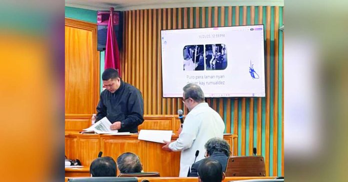 At the Sandiganbayan Third Division plunder bail hearing for former House Speaker Martin Romualdez on October 12, 2026, Deputy Special Prosecutor Omar Sagadal and witness George Villalon Jr., discuss the contents of the latter’s judicial affidavit as the flatscreen TV behind them shows a photo bearing two images of what Villalon told the court were suitcases encasing money and a message saying it contained alleged cash deliveries intended for Romualdez. PHOTO BY JOHN ERIC MENDOZA, PHILIPPINE DAILY INQUIRER