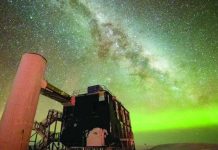 ‘Ghost particles’ from space telescope wins physics Nobel The Milky Way is seen through the middle, and the Northern Lights in green along the horizon. In the foreground is an observatory with a black building and stairs liking to a white column. YUYA MAKINO/ICECUBE/NSF