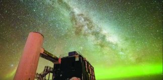 ‘Ghost particles’ from space telescope wins physics Nobel The Milky Way is seen through the middle, and the Northern Lights in green along the horizon. In the foreground is an observatory with a black building and stairs liking to a white column. YUYA MAKINO/ICECUBE/NSF
