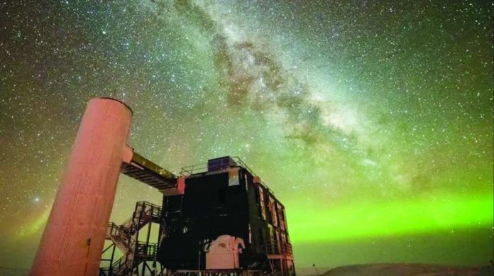 Nobel_copy_compressed_resized The Milky Way is seen through the middle, and the Northern Lights in green along the horizon. In the foreground is an observatory with a black building and stairs liking to a white column. YUYA MAKINO/ICECUBE/NSF